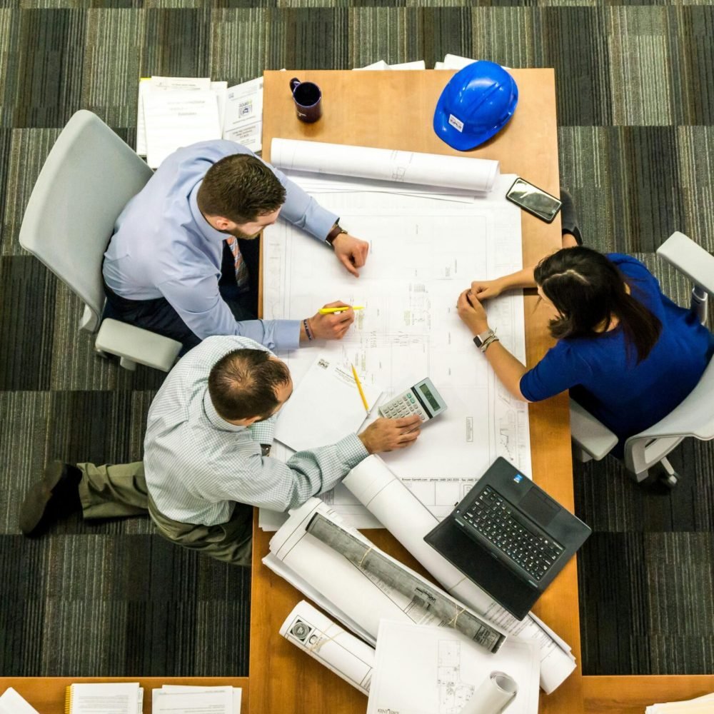 Top view of a team working on construction plans in an office setting.